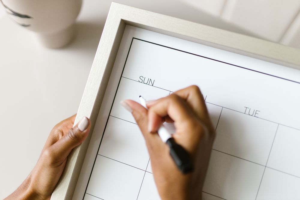 A hand writing on a wall planner
