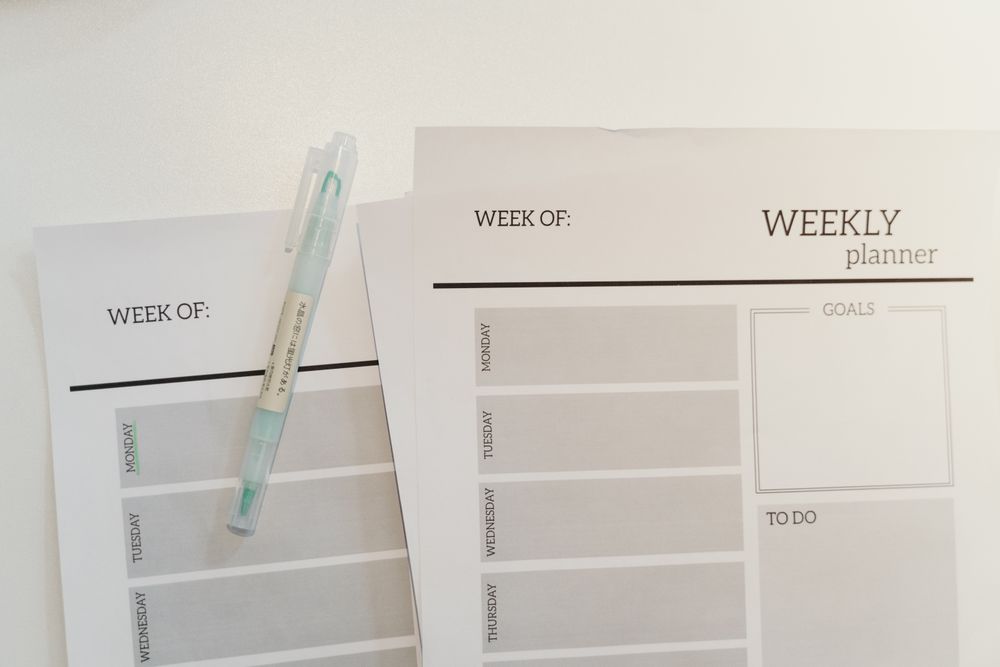 Printed weekly planner sheets with a pen on a desk