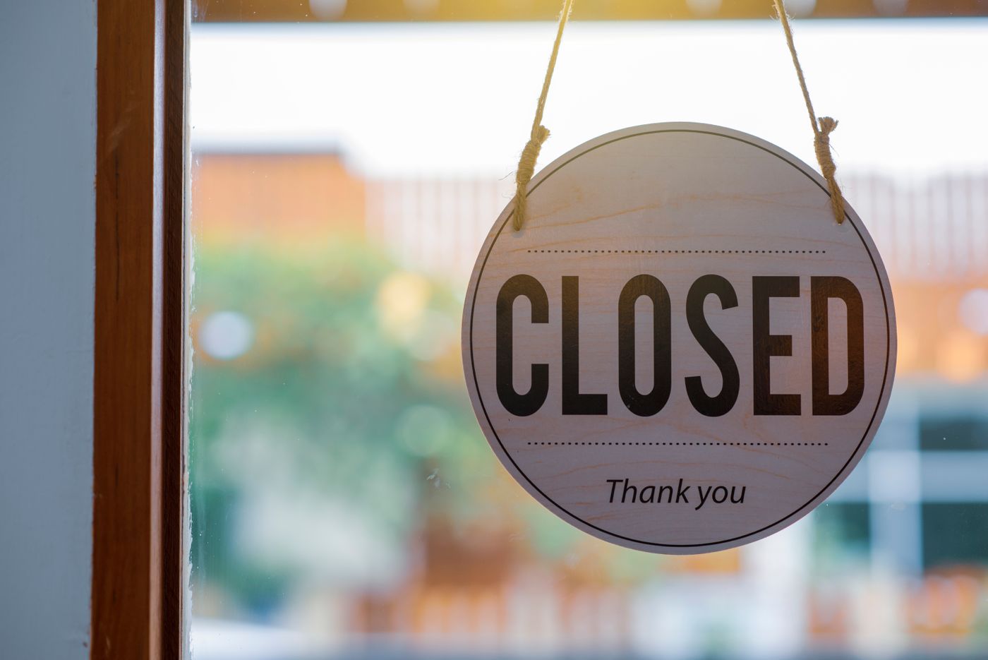 A round shop sign reading Closed, thank you, hanging in a window